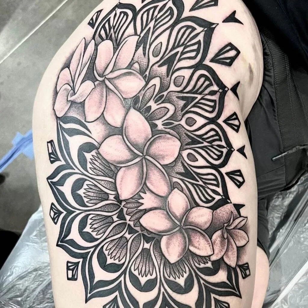 A detailed black and white floral tattoo with intricate patterns covers the upper thigh area of an individual.